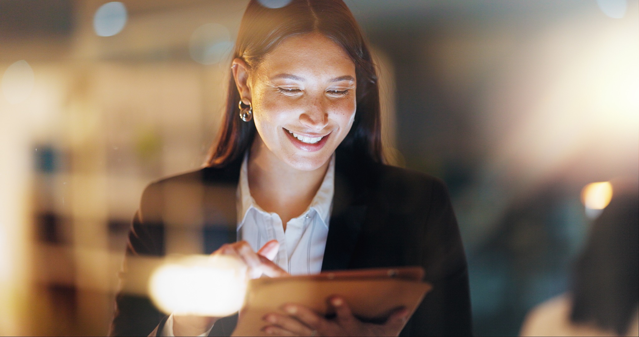 Professional using a tablet in a softly lit environment.